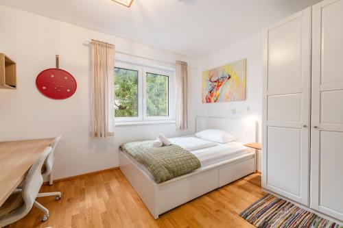 a white bedroom with a bed and a desk at Highland Moments Apartment - by myNests in Gröbming