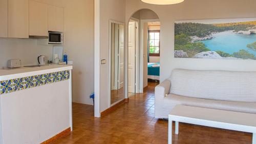 a kitchen and a living room with a couch and a table at Cala Menorca in Cala'n Porter