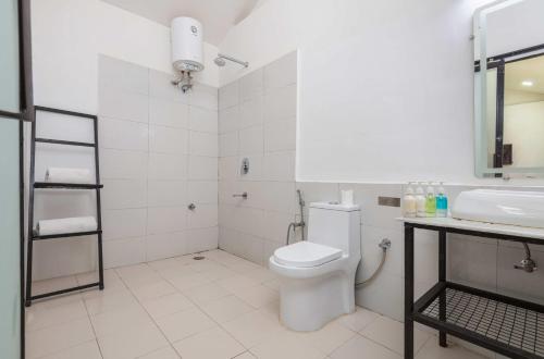 a white bathroom with a toilet and a sink at The Ayali Riverside Resort in Rishīkesh
