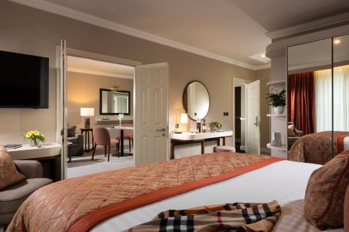 a bedroom with a large bed and a living room at Tulfarris Hotel and Golf Resort in Blessington