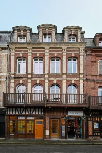 - un grand bâtiment en briques avec un balcon dans une rue dans l'établissement Studio Cosy - 250m plage, à Étretat