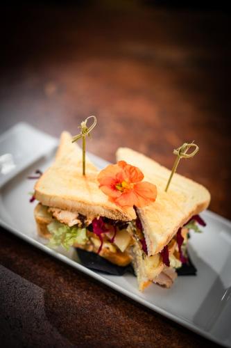 a sandwich on a plate with a flower on it at Hotel Frangart an der Weinstraße in Appiano sulla Strada del Vino