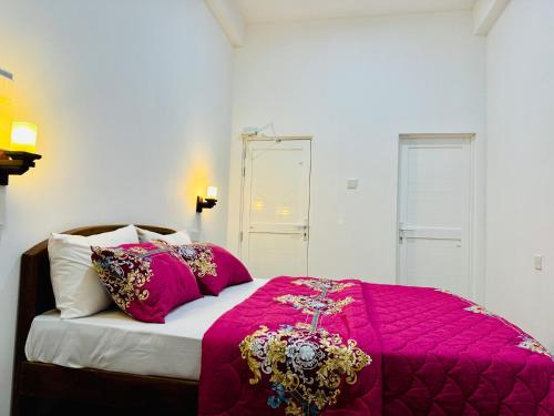a bedroom with a bed with a pink blanket and pillows at Misty5 in Pattipola