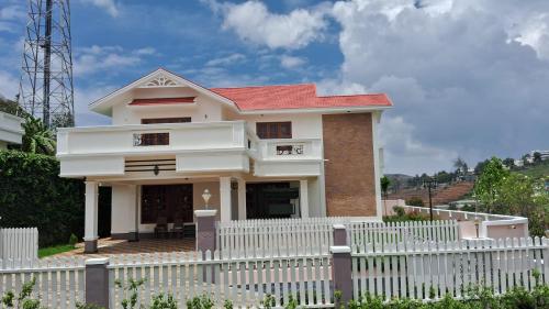 a white picket fence in front of a house at Blissfull Meadows in Ooty