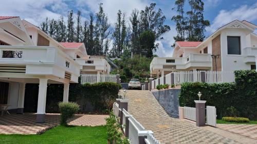 a villa with a driveway in front of a house at Blissfull Meadows in Ooty