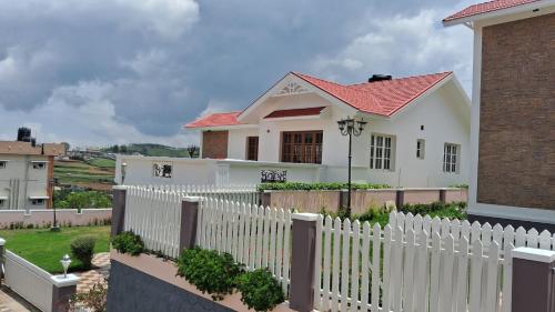 a white picket fence in front of a white house at Blissfull Meadows in Ooty