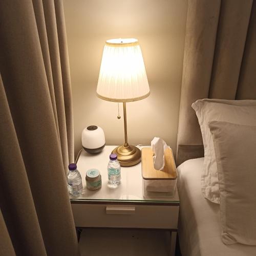 a table with a lamp and water bottles on a bed at رغيد للشقق الفندقية حائل - طريق جرير in Hail