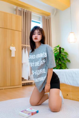 a woman kneeling on a bed in a bedroom at X-Stay in Hai Phong