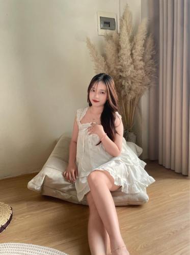 a girl in a white dress sitting on a pillow at X-Stay in Hai Phong