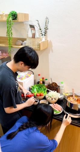 a man and a woman preparing food in a kitchen at X-Stay in Hai Phong