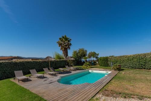 une cour arrière avec une piscine et une terrasse en bois dans l'établissement Via Mare - Apt avec splendide vue, à Grosseto-Prugna