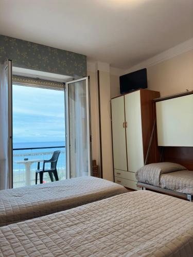 a bedroom with two beds and a view of the ocean at Hotel Svizzera in Arma di Taggia