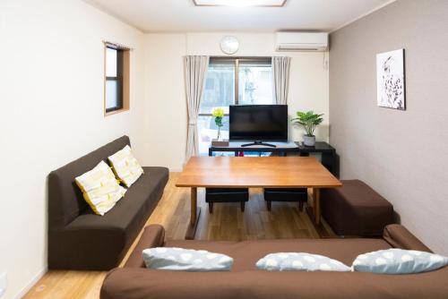 a living room with a couch and a table at アンドシェア 名古屋栄エリアの4LDK100平米 最大12名まで一軒家貸切 無料駐車場付 and SHARE in Nagoya