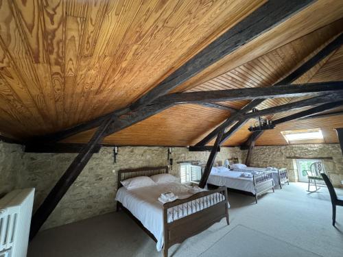 a bedroom with two beds and a wooden ceiling at Hôtel de France et de Russie in Thiviers