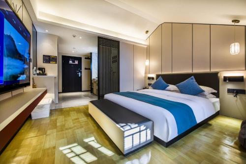 a bedroom with a large bed and a flat screen tv at Fenghuang Jiang'an Xinghe Hotel in Fenghuang
