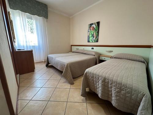 a hotel room with two beds and a window at Hotel Svizzera in Arma di Taggia
