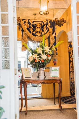 a table with a vase of flowers on it at London Lodge Hotel in London