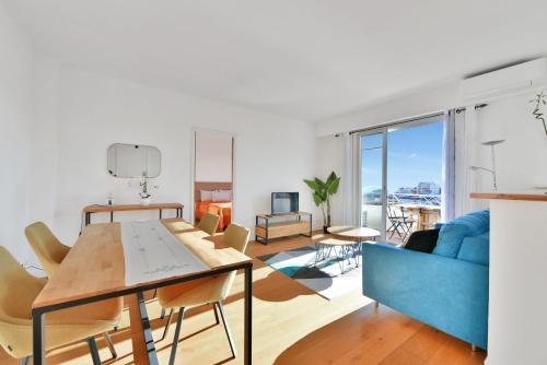 un salon avec une table et un canapé bleu dans l'établissement LE MARINE vue mer avec joli terrasse, un rêve pour les couples, à Cannes