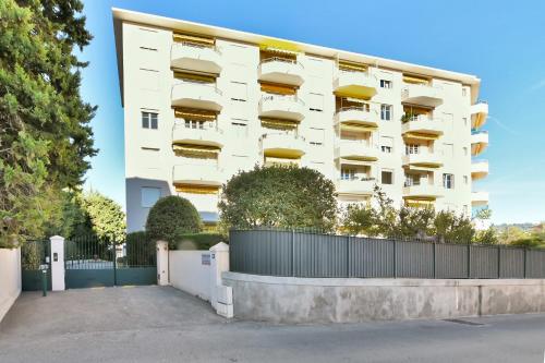 un bâtiment blanc avec une clôture devant dans l'établissement LE MARINE vue mer avec joli terrasse, un rêve pour les couples, à Cannes