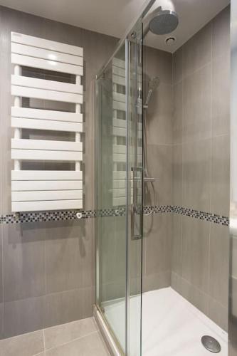 une douche avec une porte vitrée dans une salle de bain dans l'établissement La Suite des Expositions, à Paris