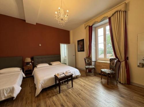a bedroom with two beds and a chandelier at Hôtel de France et de Russie in Thiviers