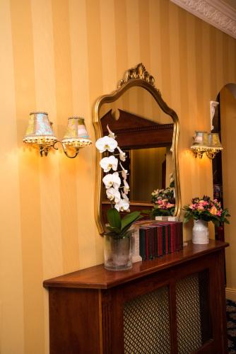 a mirror and a vase with flowers on a table at London Lodge Hotel in London