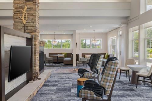 a living room with a flat screen tv and chairs at Residence Inn by Marriott Long Island Islip/Courthouse Complex in Central Islip