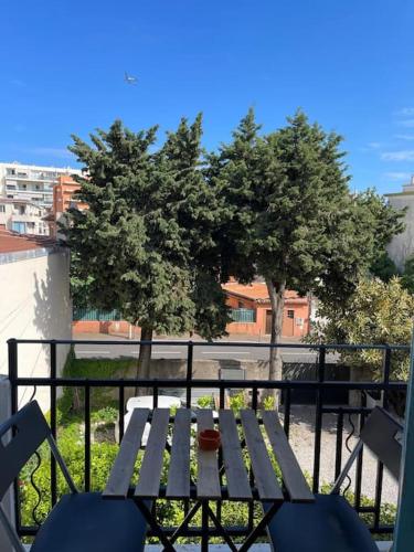 une table de pique-nique et des chaises sur un balcon avec des arbres dans l'établissement Appartement à 2 pas de la mer et Parking privé, à Nice