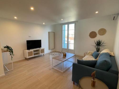 un salon avec un canapé bleu et une télévision dans l'établissement Appartement à 2 pas de la mer et Parking privé, à Nice