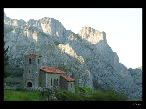 an old church in front of a mountain at Viviendas Rurales El Cantón in Cucayo