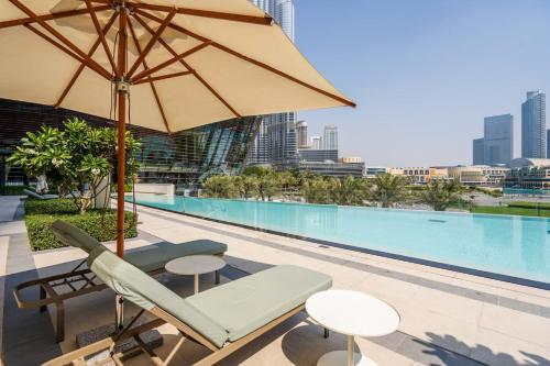 a pool with a chair and an umbrella and a table at GuestReady - Elegant 1BR l Premium Amenities in Dubai