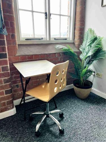 a desk and a chair in a room with a plant at City Mill - Next to Town Centre Shopping and Restaurants - Free Parking in Burton upon Trent