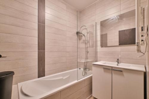 a white bathroom with a tub and a sink at Marmotte 104 in Les Deux Alpes