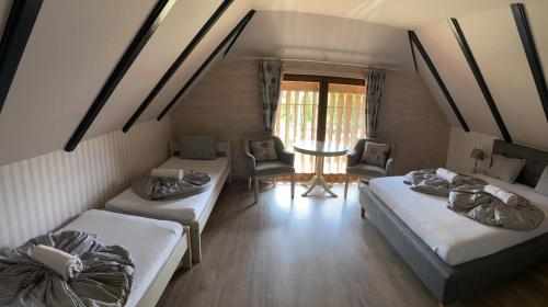 a room with two beds and a table and chairs at Csodaszarvas Vendégházak in Rábahidvég
