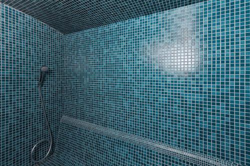 a blue tiled bathroom with a shower with a light at RHOLL Pension & Restaurant in Hámry