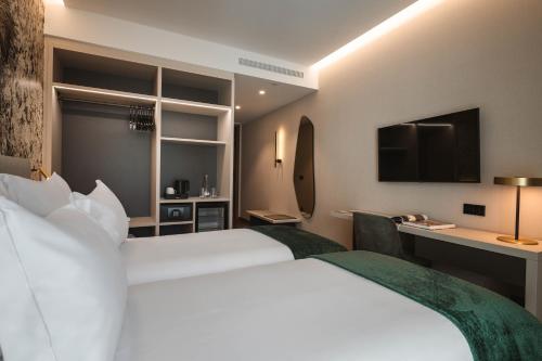 a hotel room with a large white bed and a desk at Dolinas Climbing Hotel in Porto de Mós
