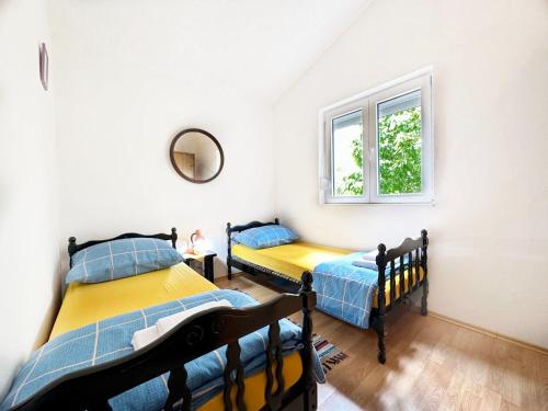 two twin beds in a room with a window at House Tamy - with jacuzzi in Srijane
