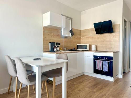 une cuisine blanche avec une table et des chaises blanches dans l'établissement Appartement 2 pièces, à proximité de la plage, à Port-la-Nouvelle