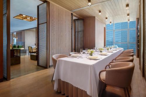 a long dining room with a long table and chairs at The Mercury Garden Shenzhen Nanshan, A Tribute Portfolio Hotel in Shenzhen