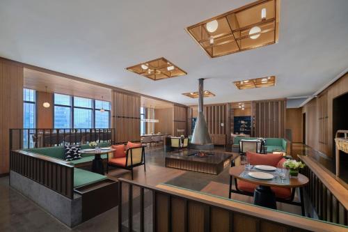 a large living room with tables and chairs at The Mercury Garden Shenzhen Nanshan, A Tribute Portfolio Hotel in Shenzhen