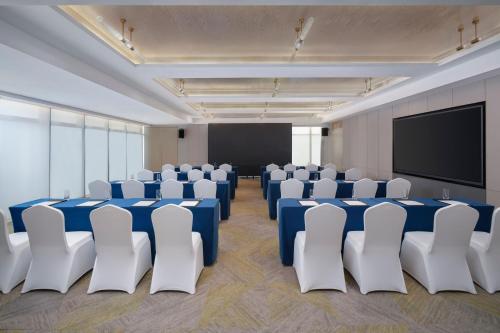 a conference room with blue and white chairs and a screen at The Mercury Garden Shenzhen Nanshan, A Tribute Portfolio Hotel in Shenzhen
