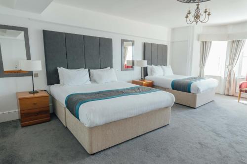 a hotel room with two beds and a chandelier at Queens Hotel & Spa in Brighton & Hove