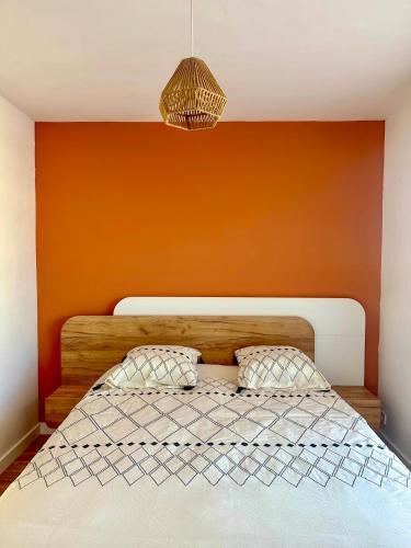 une chambre avec un lit avec un mur orange dans l'établissement Appartement 2 pièces, à proximité de la plage, à Port-la-Nouvelle