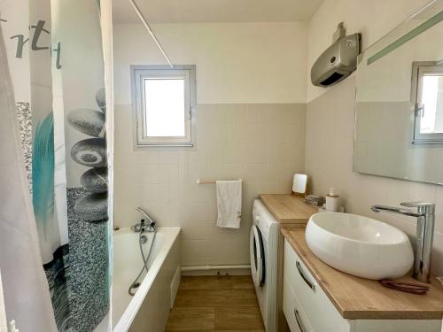 La salle de bains blanche est pourvue d'un lavabo et d'une baignoire. dans l'établissement Appartement 2 pièces, à proximité de la plage, à Port-la-Nouvelle