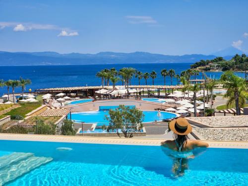 a woman in a hat in a swimming pool at a resort at Miraggio Thermal Spa Resort in Paliouri
