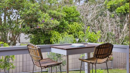 a table with two chairs and a glass of wine at Boronia Oasis - Tranquil Oasis By The Creek, Sleeps 4 in Sawtell