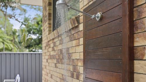 a wooden door on a brick wall with water coming out at Boronia Oasis - Tranquil Oasis By The Creek, Sleeps 4 in Sawtell