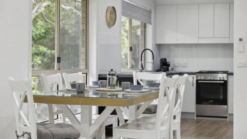 a kitchen with a table and white chairs in a kitchen at Boronia Oasis - Tranquil Oasis By The Creek, Sleeps 4 in Sawtell