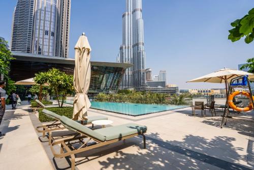 a pool with a chaise lounge and an umbrella at GuestReady - Elegant 1BR l Premium Amenities in Dubai