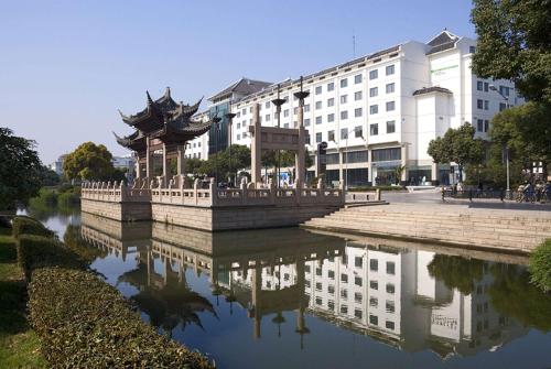 a reflection of a building in a body of water at Wyndham Garden Suzhou in Suzhou
